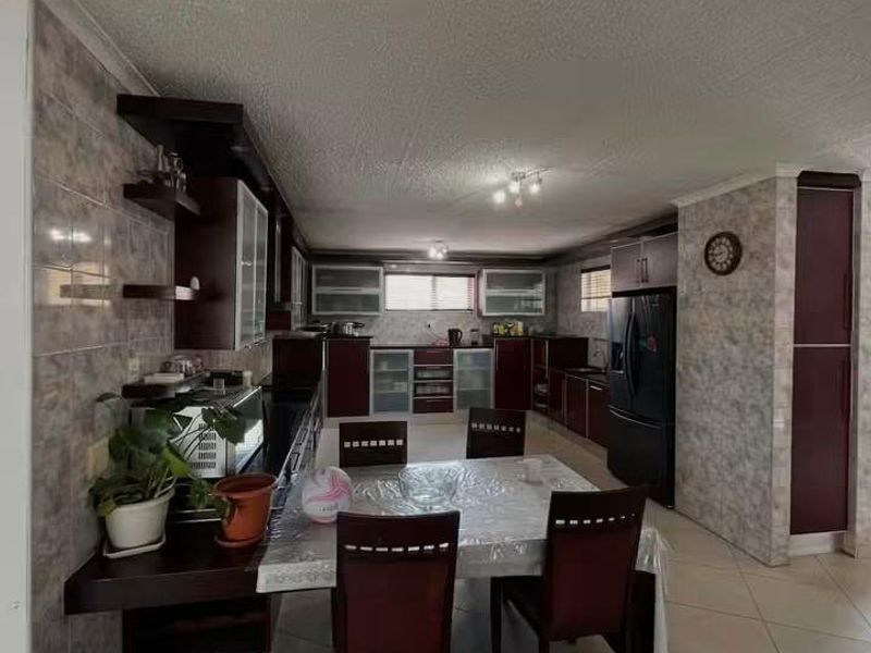 Spacious open-plan kitchen and dining area featuring dark wood cabinetry, tiled flooring, and a textured ceiling finish.