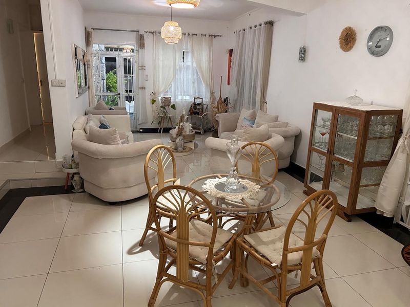 An open-plan living and dining area featuring large format floor tiles, neutral walls, and direct access to an outdoor patio space.