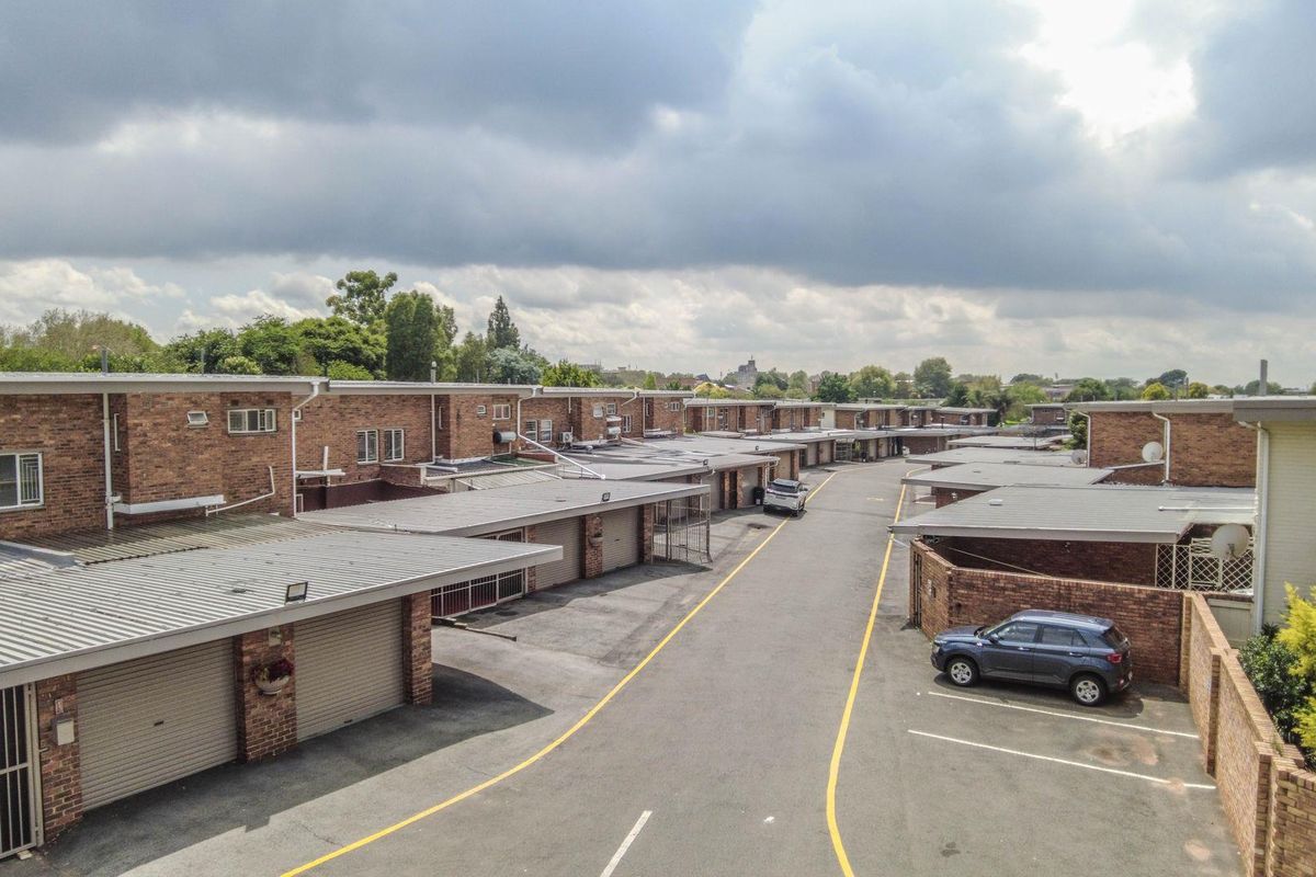 Aerial view of a townhouse complex featuring rows of brick units with attached garages and paved access roads.
