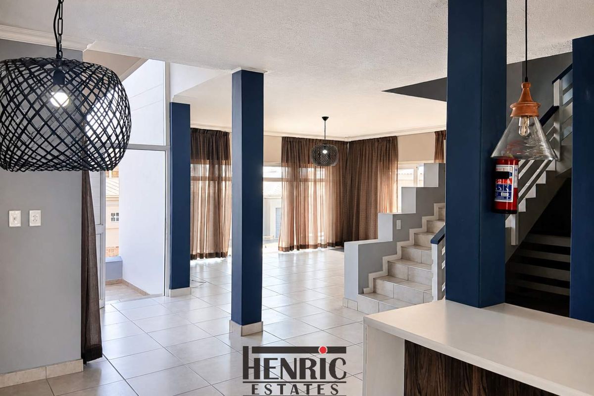 Spacious open-plan living area featuring tiled floors, a central staircase, and modern structural columns, offering a versatile layout for various living arrangements.