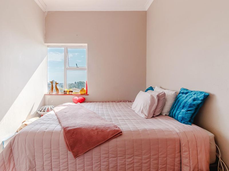 A bright bedroom featuring a window with natural light and neutral wall finishes.