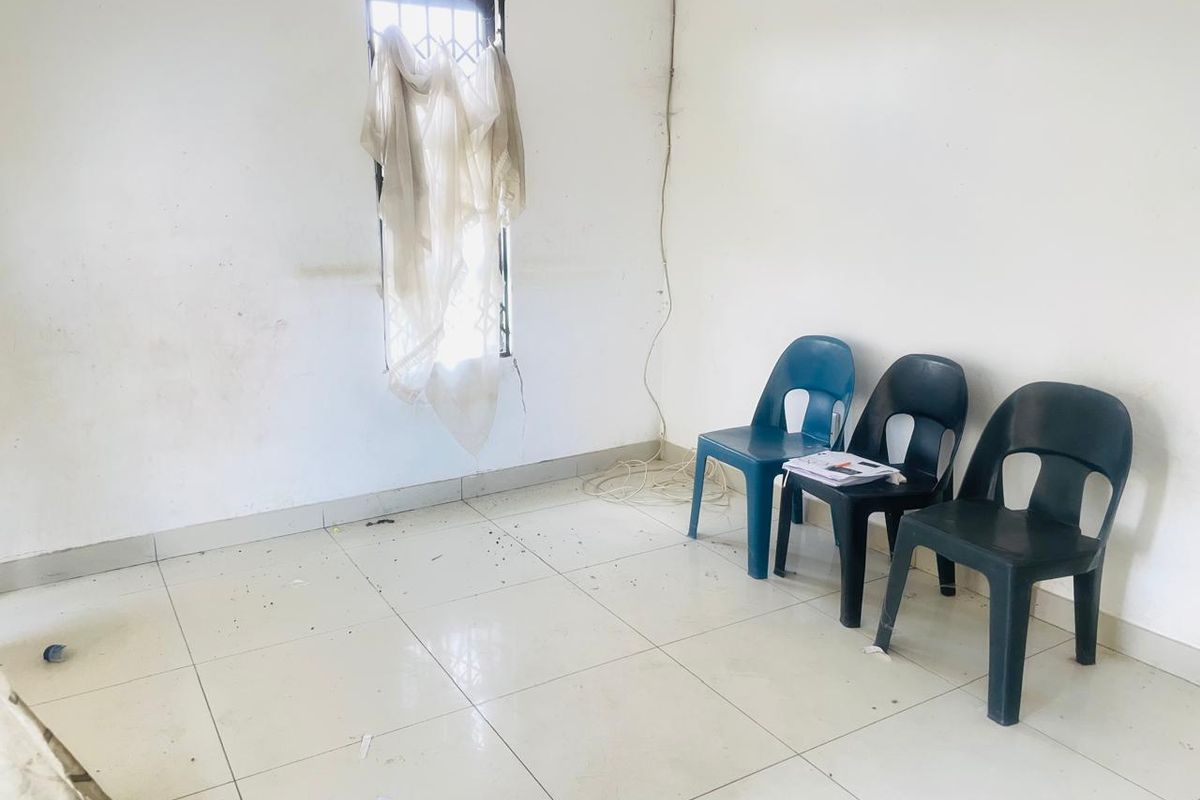A sparse room featuring tiled flooring and a window with security bars, currently in need of maintenance and cosmetic updates.