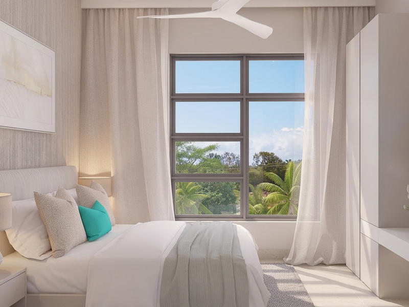 A modern, well-lit bedroom featuring a built-in wardrobe, integrated desk, and ceiling fan, with large windows offering a pleasant outdoor view.