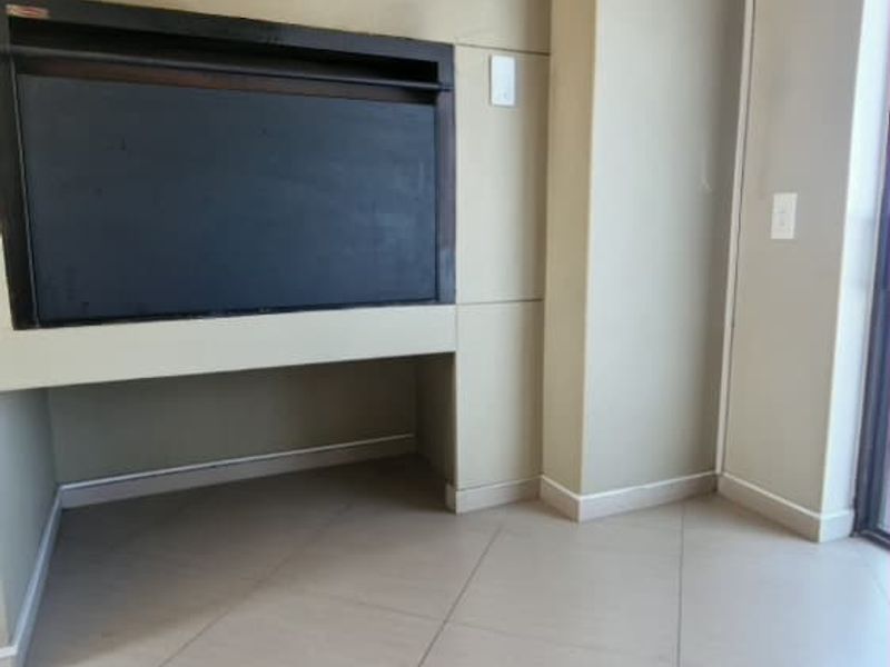 An empty living room featuring a built-in fireplace, neutral tiled flooring, and cove cornicing, offering a clean canvas for interior design.