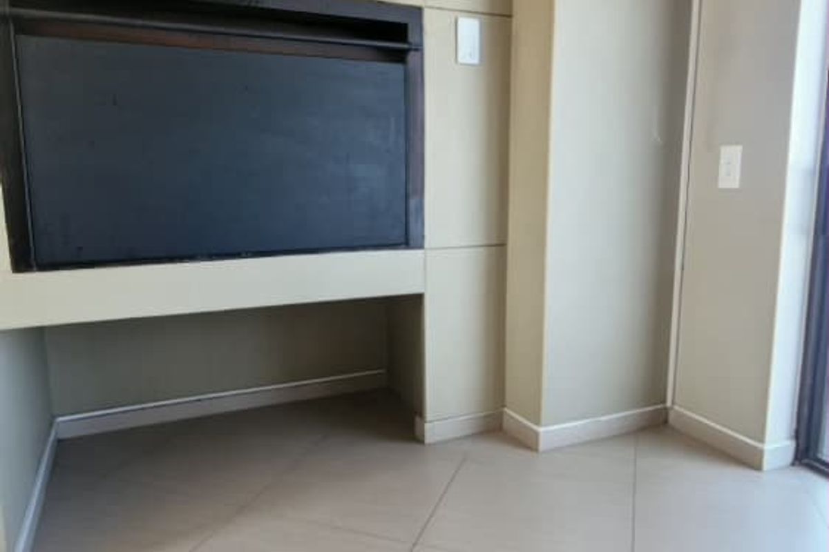 An empty living room featuring a built-in fireplace, neutral tiled flooring, and cove cornicing, offering a clean canvas for interior design.