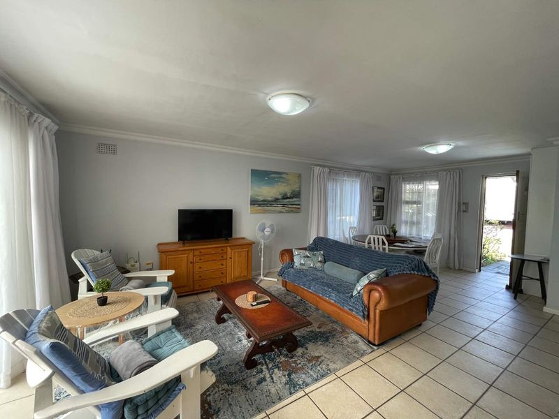 Spacious open-plan living and dining area featuring neutral wall finishes, tiled flooring, and natural light through large windows.