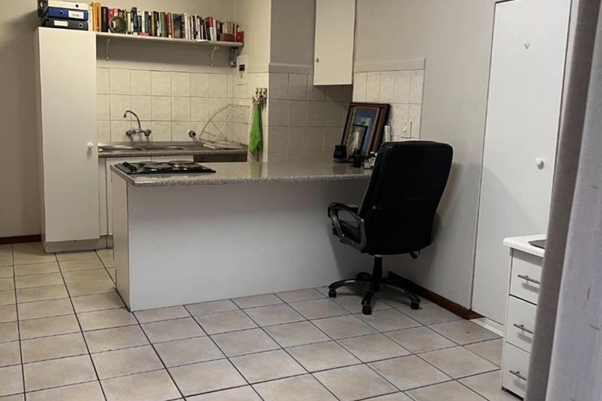 A functional kitchen area featuring built-in cabinetry, a hob, tiled backsplash, and tiled flooring, offering a practical layout for daily use.