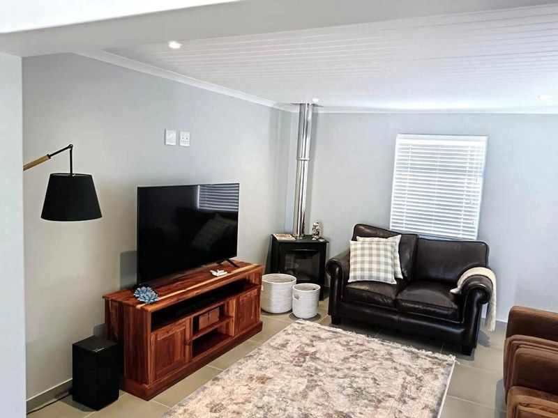 A well-maintained living room featuring a wood-burning fireplace, tiled flooring, and recessed lighting, creating a comfortable and functional space.