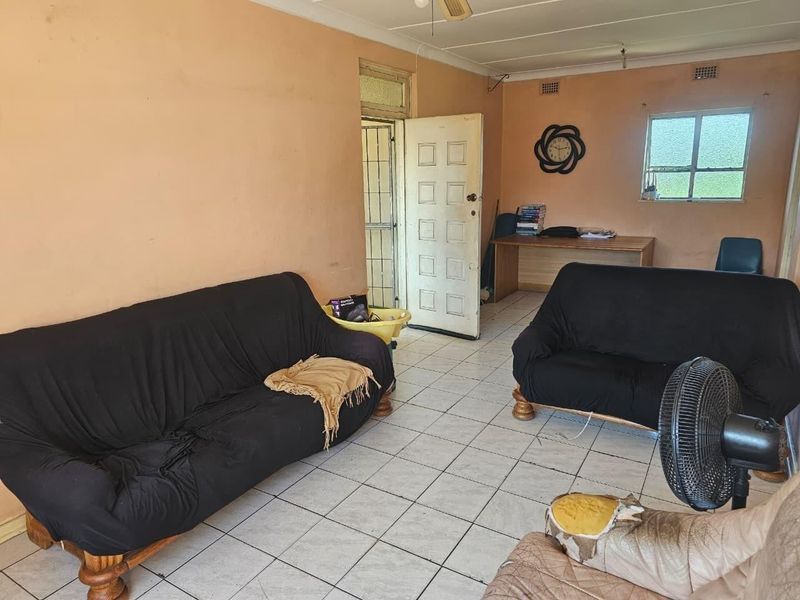 A living room area featuring tiled flooring, a security gate, and a casement window, requiring cosmetic updates to improve the overall aesthetic.