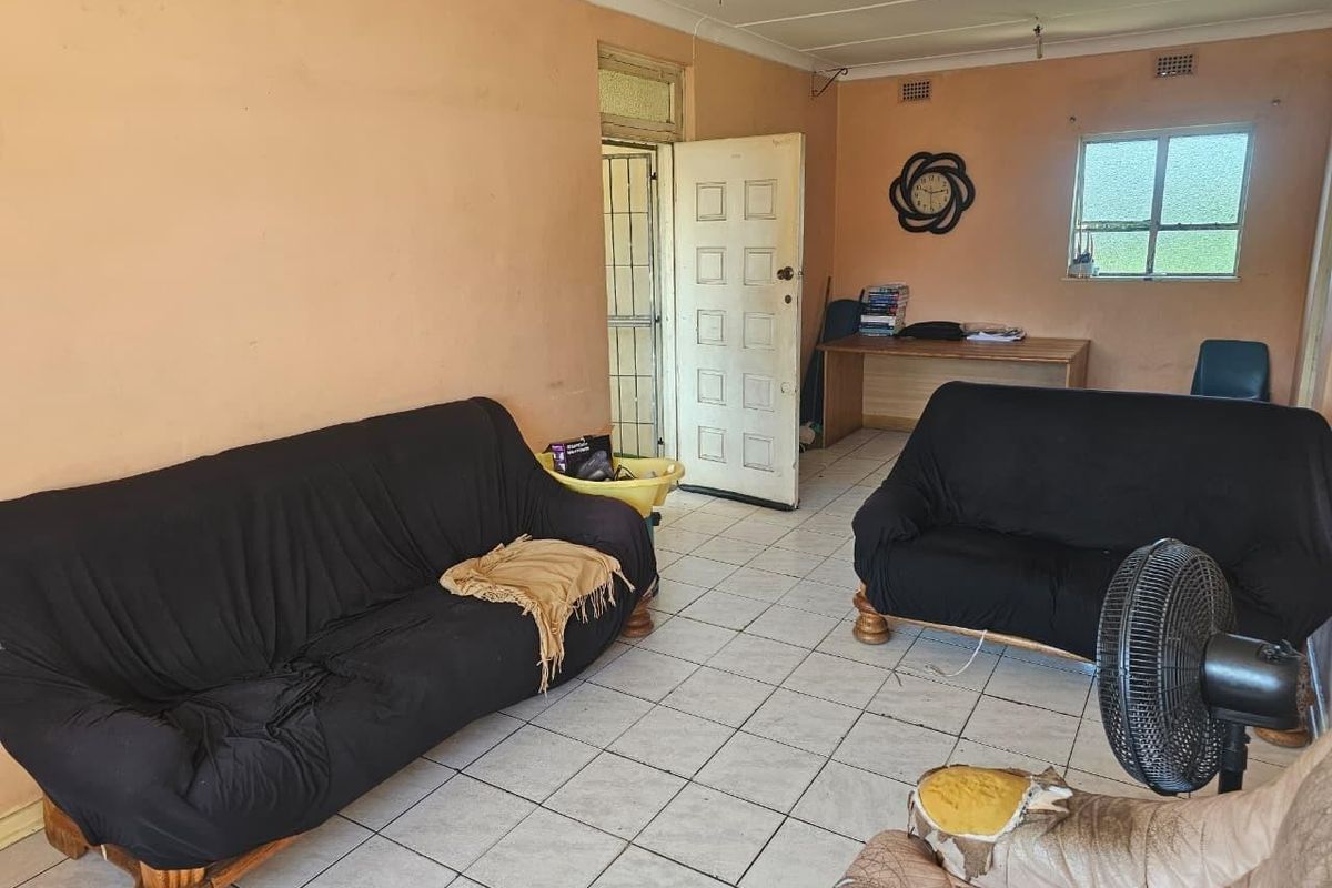 A living room area featuring tiled flooring, a security gate, and a casement window, requiring cosmetic updates to improve the overall aesthetic.