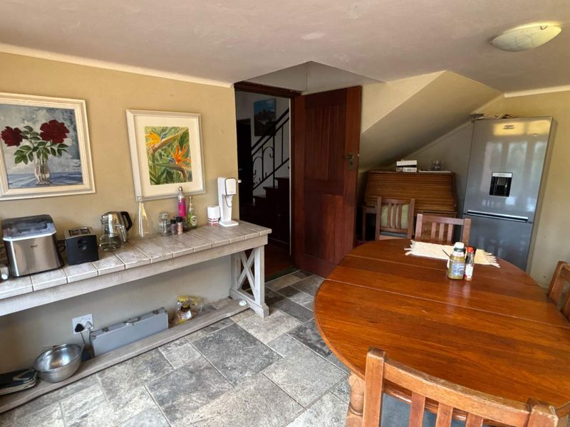 Open plan dining and utility area featuring tiled flooring, a built-in wooden console, and access to an internal staircase.