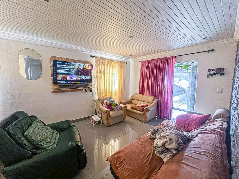 A living room featuring tiled flooring, a tongue and groove ceiling, and a sliding glass door providing access to the exterior.