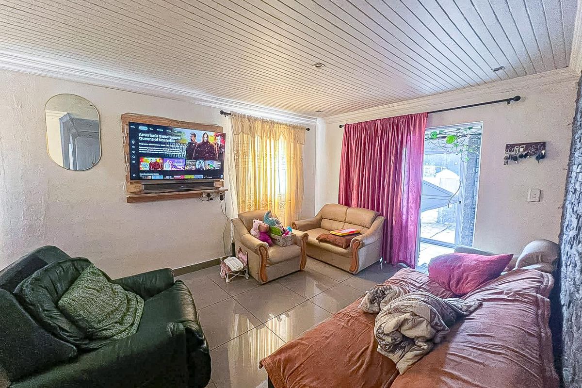 A living room featuring tiled flooring, a tongue and groove ceiling, and a sliding glass door providing access to the exterior.