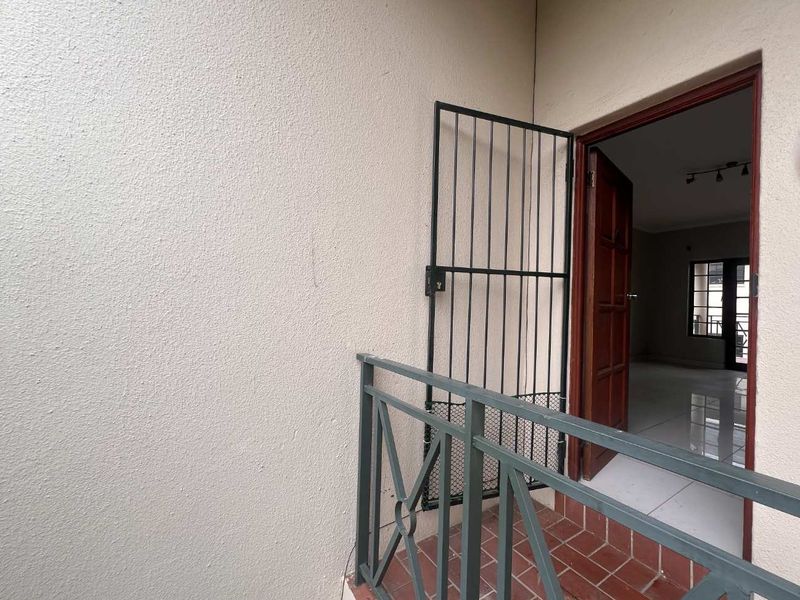 A small balcony area featuring a security gate, metal railing, and tiled flooring, providing access to the interior living space.
