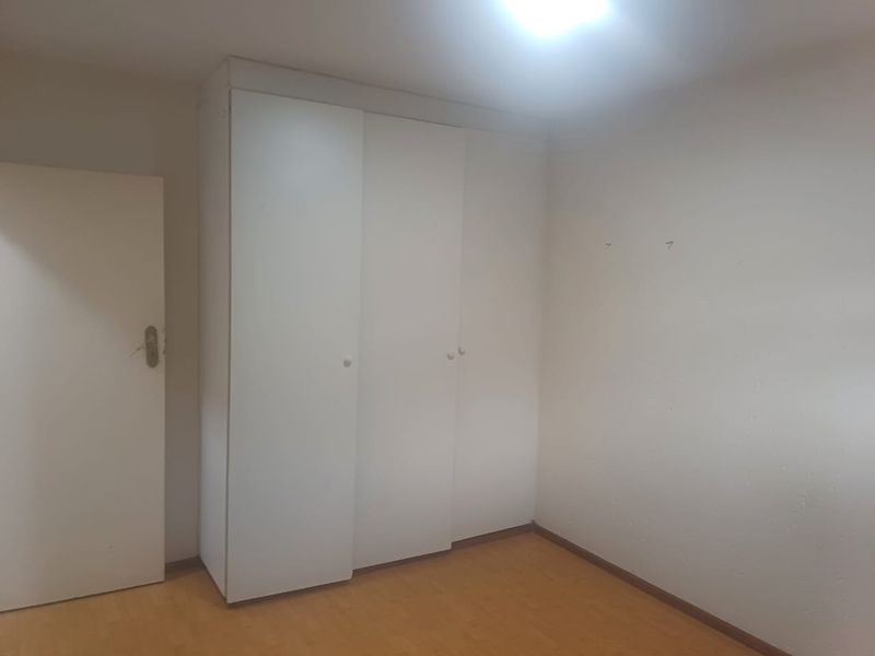 An empty bedroom featuring laminate flooring and built-in cupboards, providing a neutral canvas for personalization.