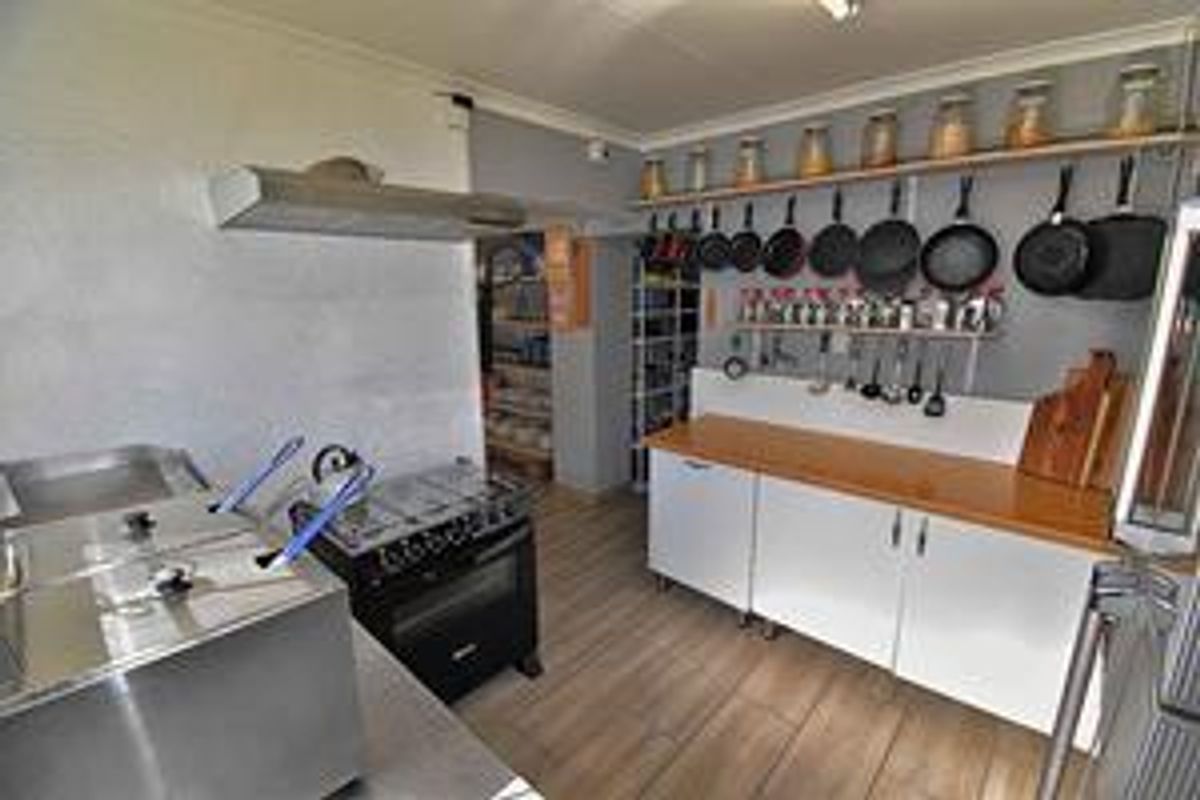 A functional commercial kitchen space featuring stainless steel appliances, wooden countertops, and wall-mounted storage racks for professional culinary use.