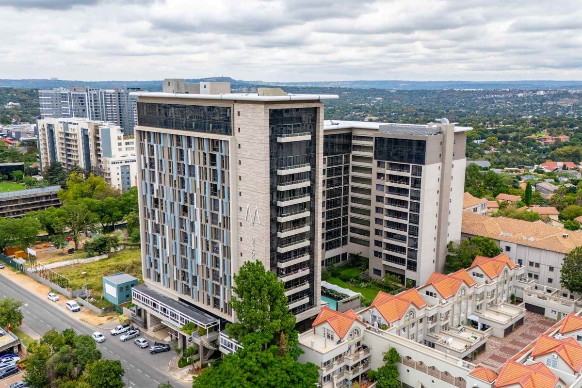Aerial view of a modern high-rise apartment complex featuring contemporary architectural design, glass facades, and surrounding urban landscape.