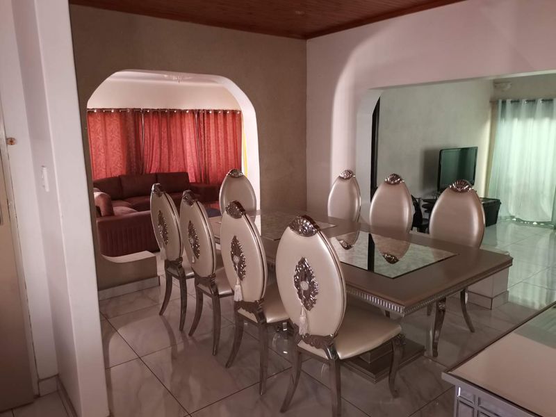 Open plan dining area featuring tiled flooring, arched architectural transitions, and timber ceiling paneling, connecting to an adjacent living space.