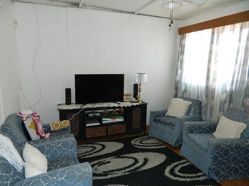 A living room featuring visible wall paneling and exposed wiring, offering a dated aesthetic that could benefit from cosmetic updates and modern finishes.