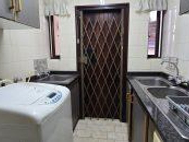 Functional scullery area featuring double stainless steel sinks, granite countertops, ample built-in cabinetry, and a secure access door.