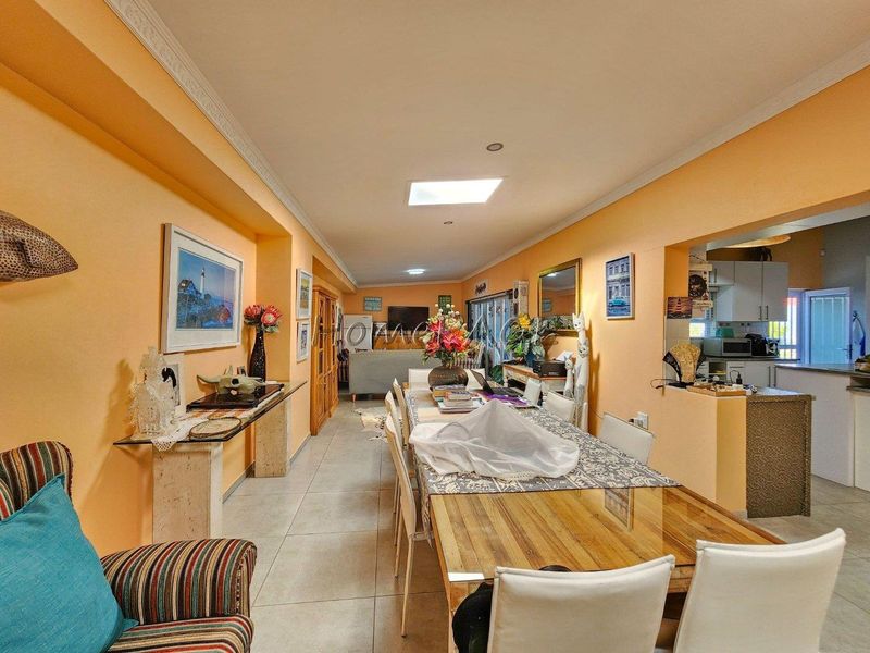 Open plan dining and living area featuring tiled flooring, skylight, and integrated kitchen space with cabinetry.