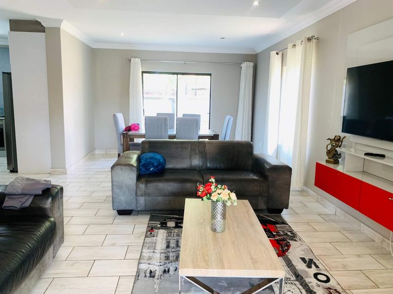 Spacious open-plan living and dining area featuring neutral wall tones, tiled flooring, and direct access to the outdoor space through sliding glass doors.
