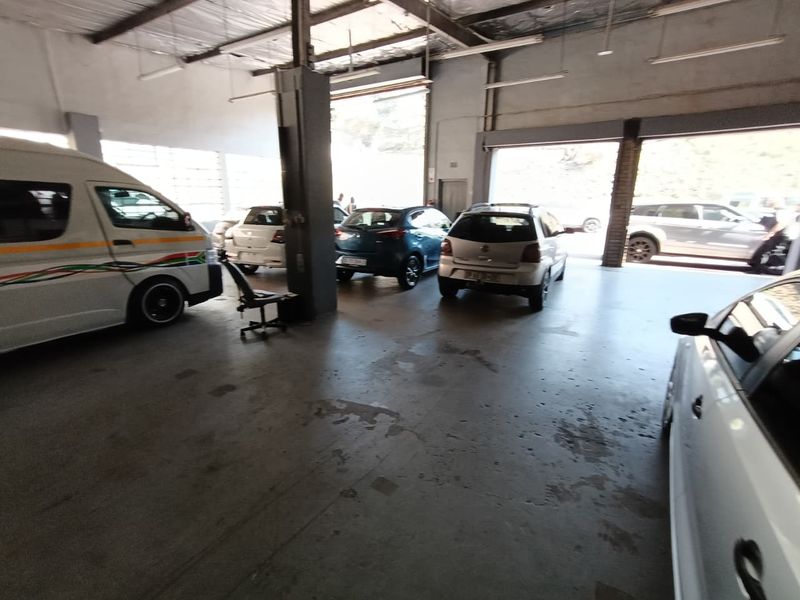 Spacious industrial garage featuring concrete flooring, exposed steel roof structure, and large roller shutter doors, suitable for vehicle storage or workshop use.