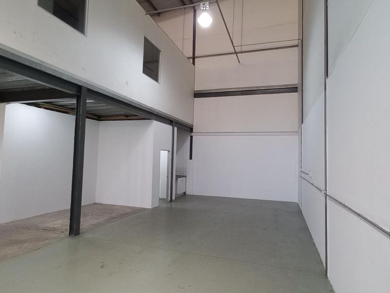 Spacious industrial warehouse unit featuring a mezzanine level, high ceilings, concrete flooring, and clean white-painted walls, suitable for various commercial or storage uses.