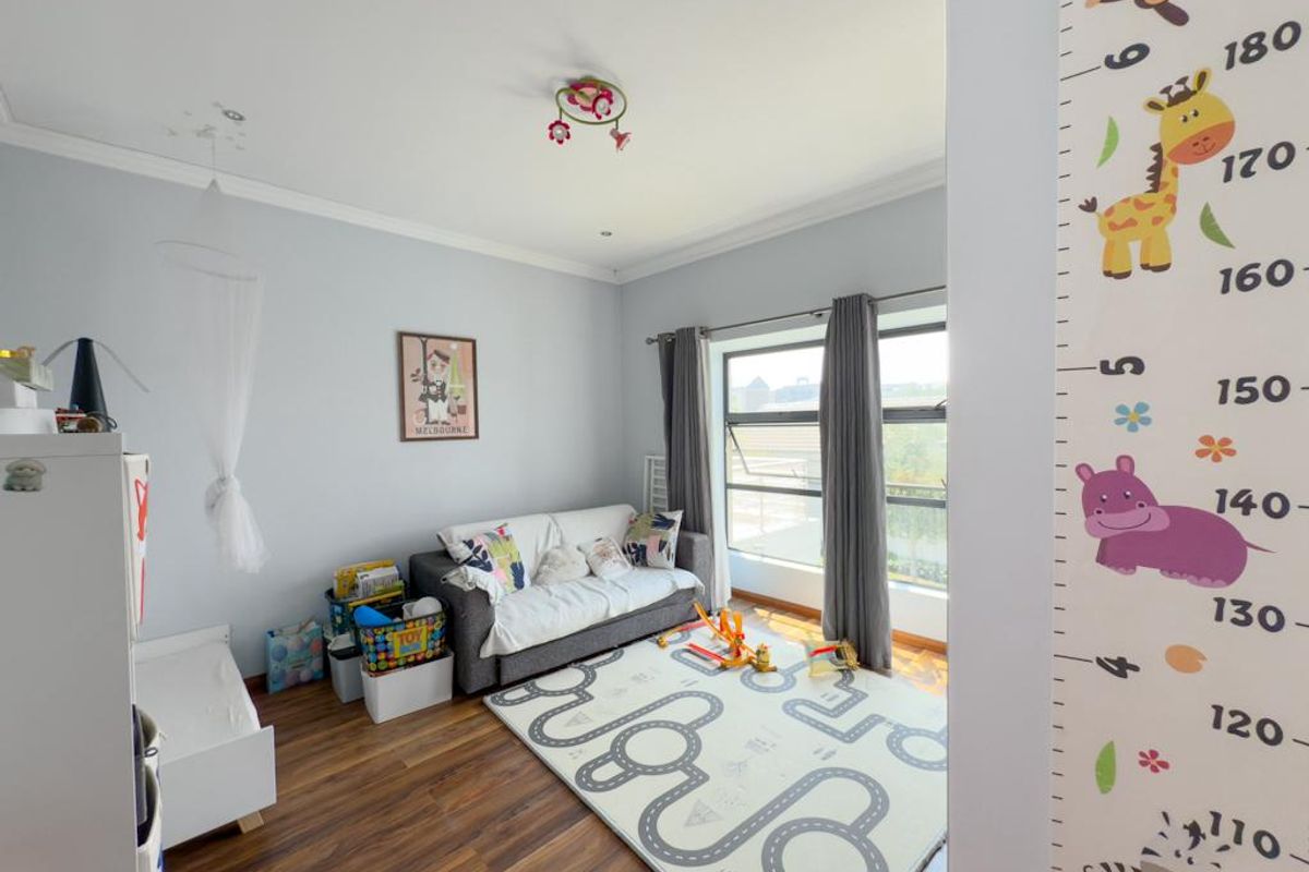 A bedroom featuring timber flooring, large windows with curtains, and a ceiling-mounted light fixture.