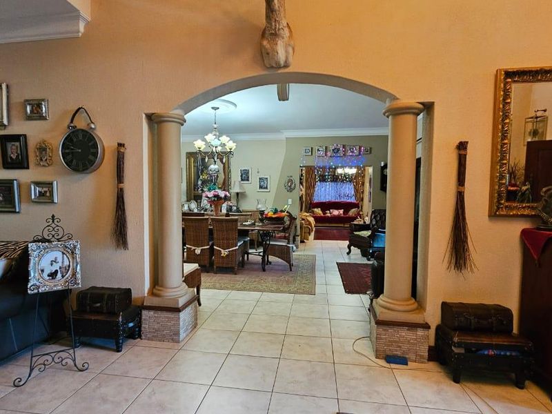 Spacious open-plan living and dining area featuring a decorative arched entryway with columns, tiled flooring, and neutral wall finishes.