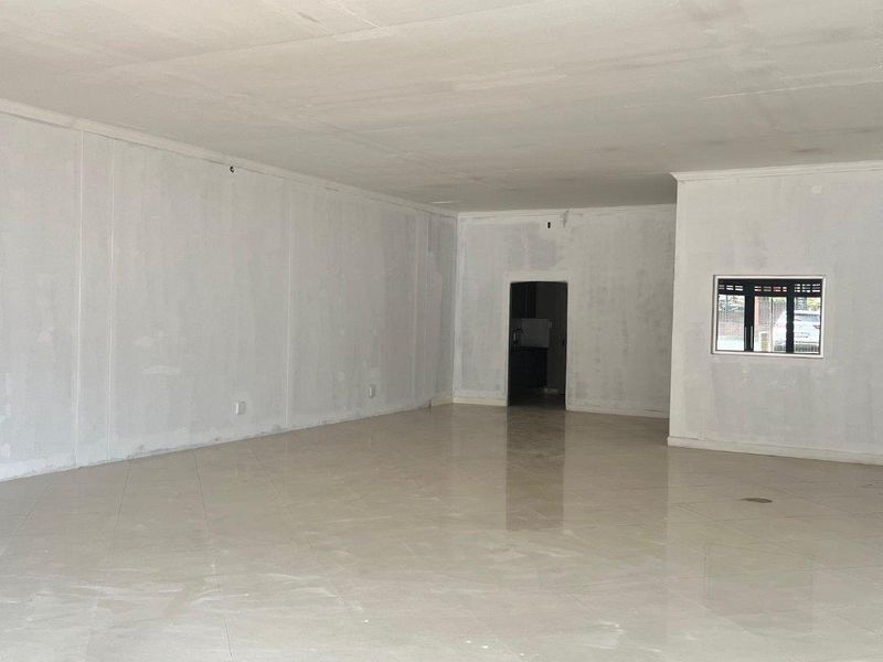 A spacious, open-plan retail area featuring polished tiled flooring and freshly plastered walls, awaiting final finishes and customization.
