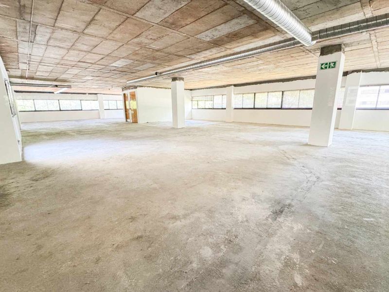 Expansive open-plan commercial space featuring exposed concrete ceilings, industrial ducting, and large windows, offering a blank canvas for custom office or retail fit-outs.