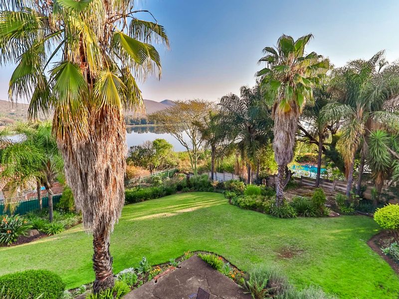 A well-maintained garden featuring mature palm trees, lush lawn, and scenic views of the nearby lake and surrounding landscape.