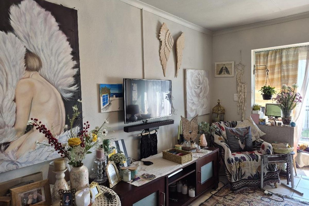 A living room area featuring a wall-mounted television and access to an outdoor space through a sliding glass door.