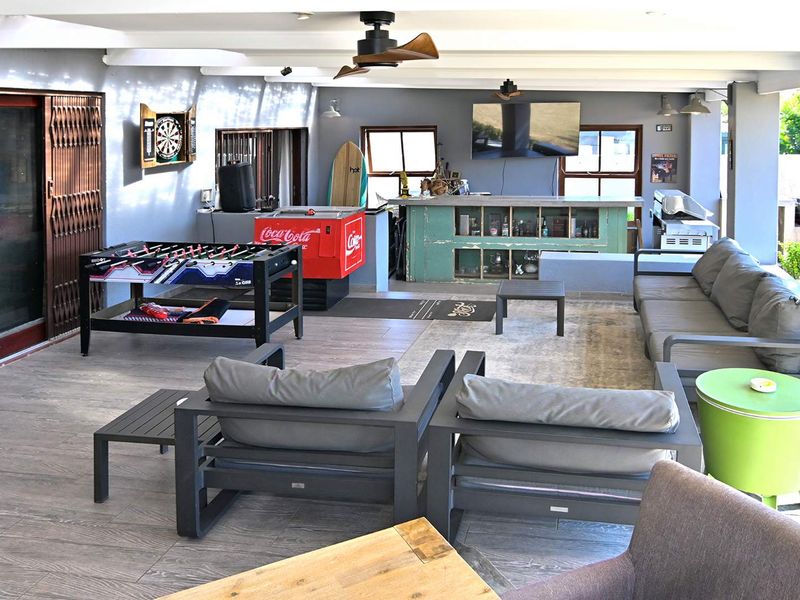 Spacious covered patio entertainment area featuring a built-in bar, tiled flooring, and ceiling fans, ideal for outdoor social gatherings.