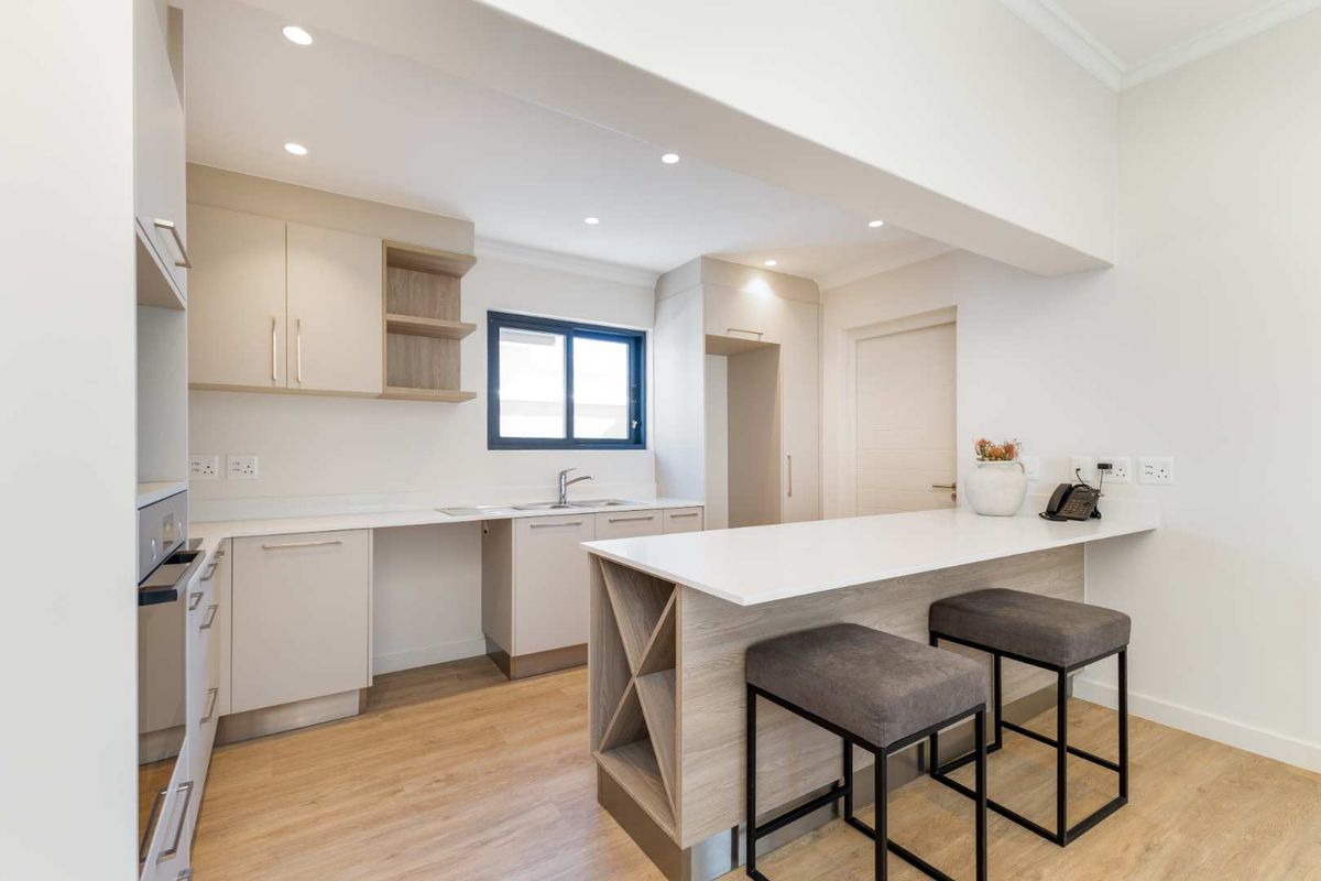 Modern kitchen featuring sleek cabinetry, stone countertops, a breakfast bar, and integrated oven, finished with high-quality laminate flooring and recessed lighting.