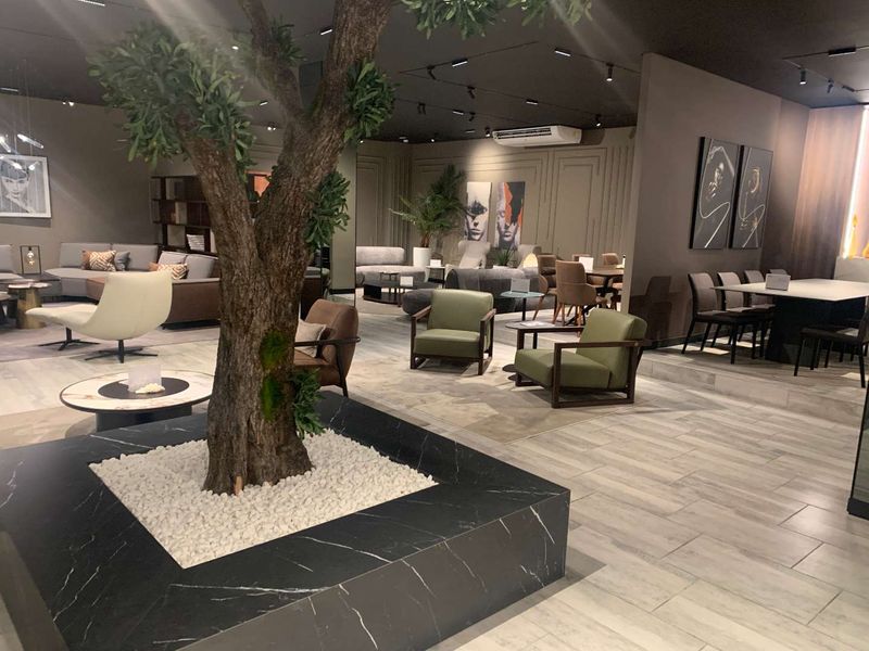 Spacious open-plan retail showroom featuring modern marble-look tile flooring, recessed track lighting, and sophisticated wall molding details.