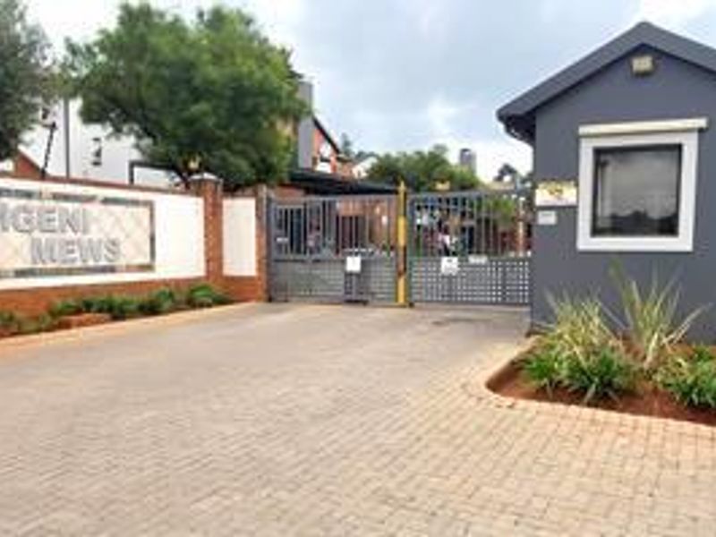The entrance to Mgeni Mews featuring a secure gated access point, guard house, and paved driveway.