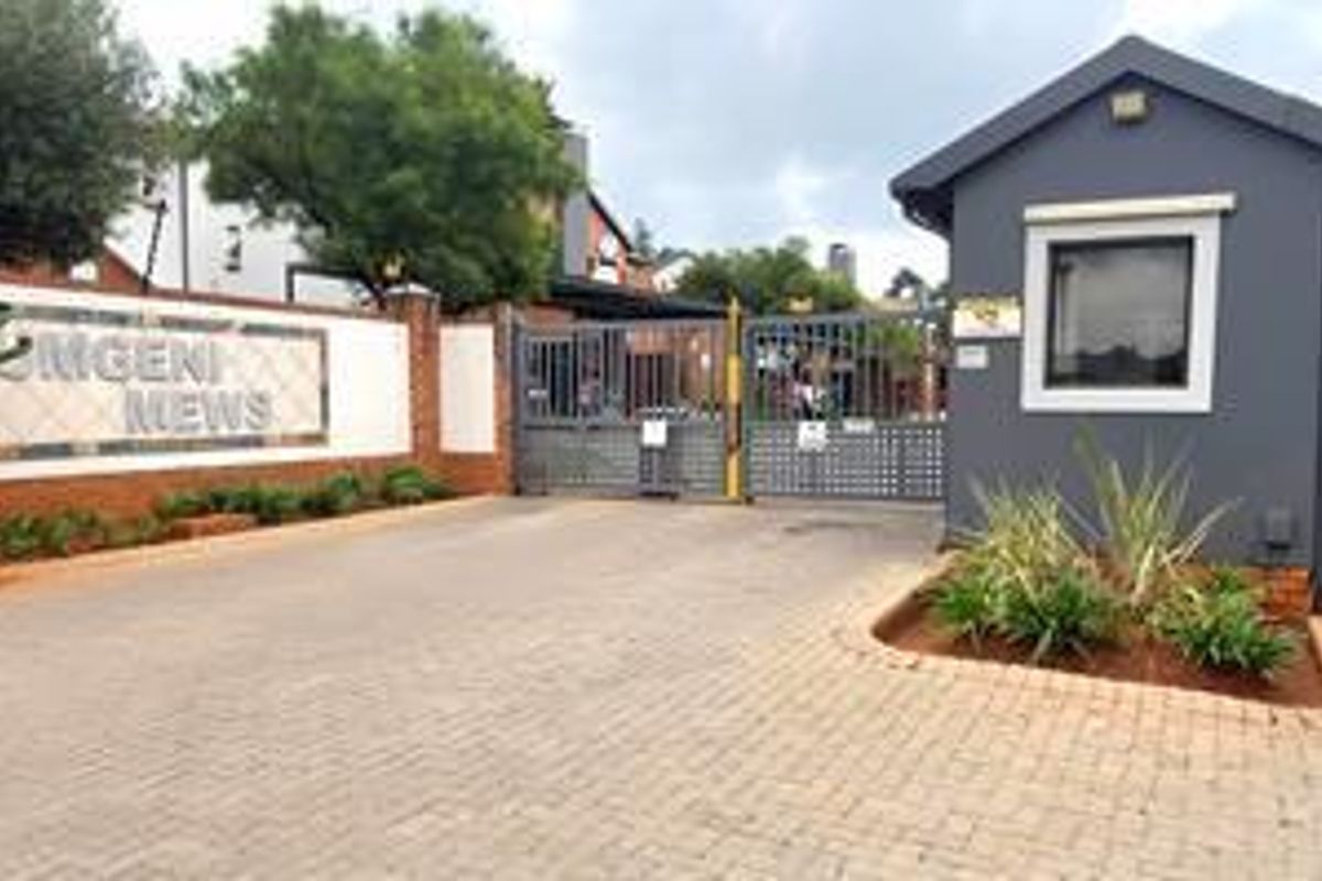 The entrance to Mgeni Mews featuring a secure gated access point, guard house, and paved driveway.