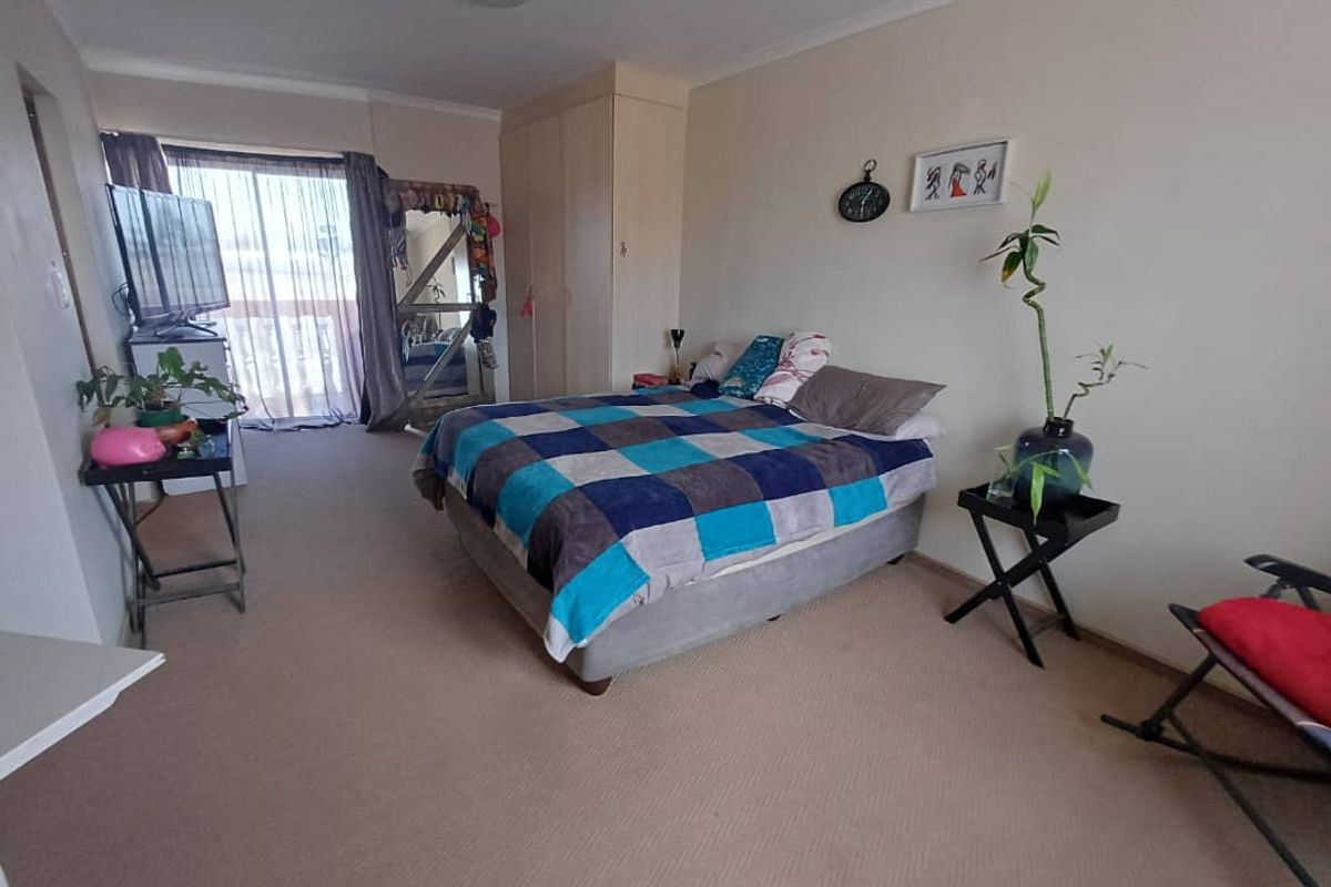 Spacious bedroom featuring built-in cupboards and sliding door access to a private balcony, providing natural light and ventilation.