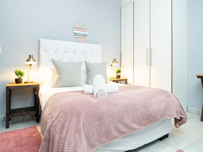 A well-maintained bedroom featuring neutral walls, tiled flooring, and a spacious built-in wardrobe for ample storage.