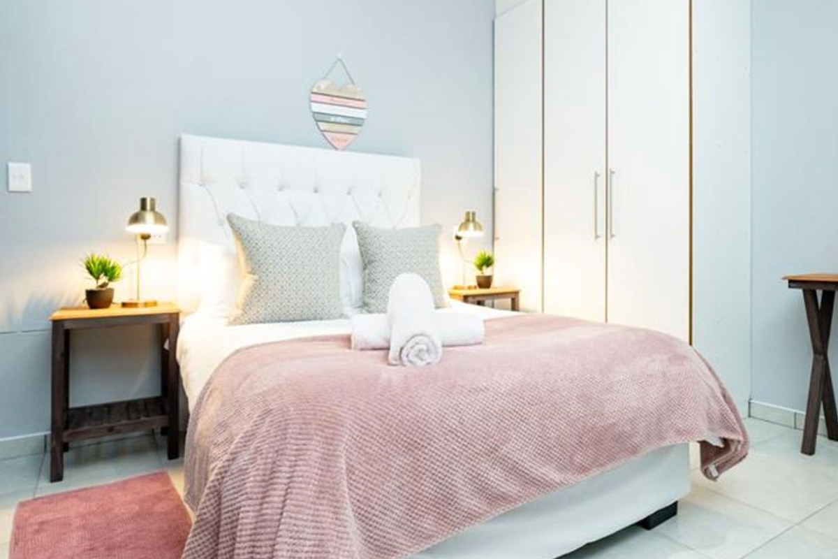 A well-maintained bedroom featuring neutral walls, tiled flooring, and a spacious built-in wardrobe for ample storage.