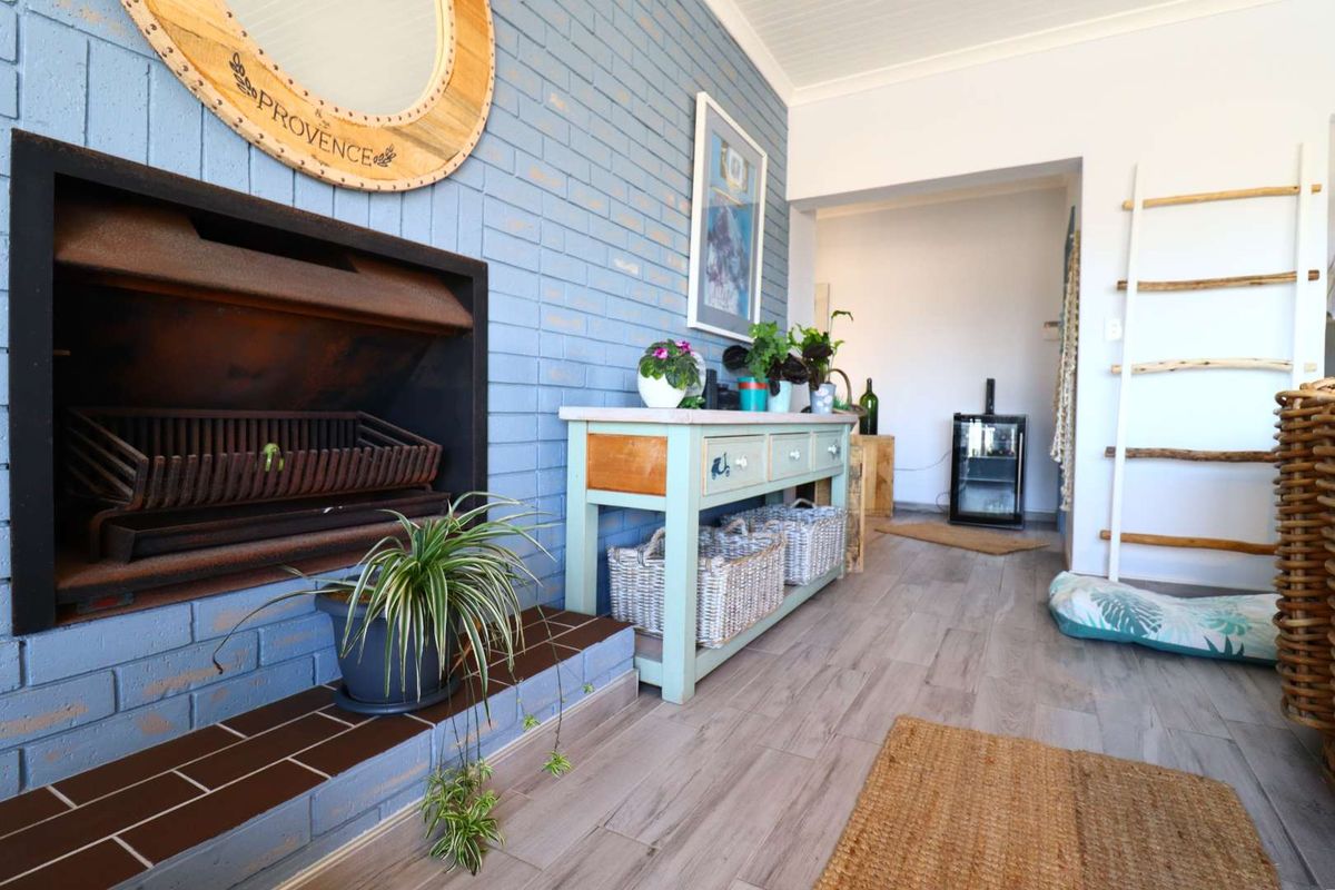 Living area featuring a blue painted brick fireplace with a tiled hearth and wood-look laminate flooring.
