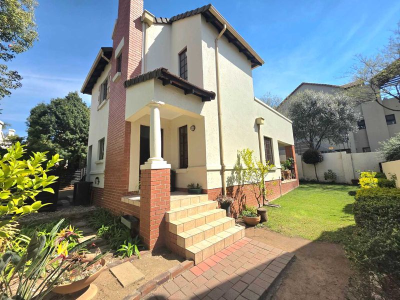 A charming two-story house featuring a brick chimney, covered entrance porch with a decorative column, and a well-maintained front garden area.