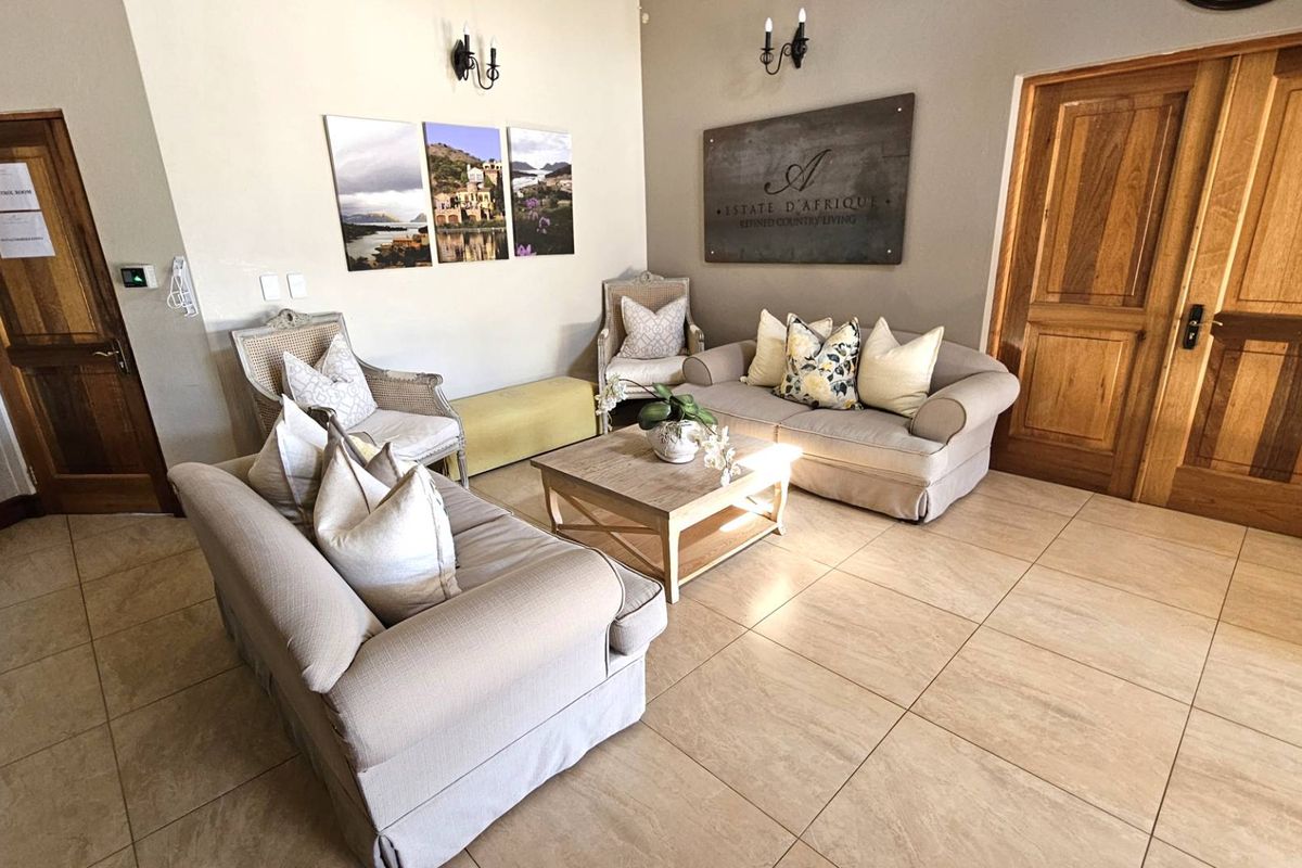 A well-maintained interior reception or lounge area featuring tiled flooring, wooden double doors, and wall-mounted lighting fixtures.