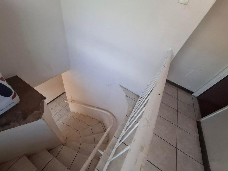 A functional interior staircase featuring tiled steps and a metal balustrade, showing signs of wear and requiring cosmetic maintenance.