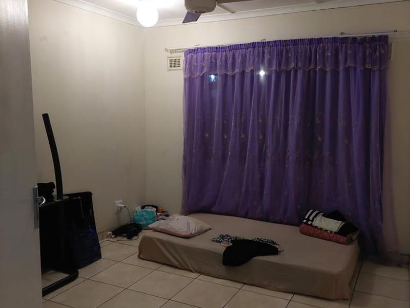 A simple bedroom featuring tiled flooring and a ceiling fan, offering a functional space ready for personalization and updated interior styling.
