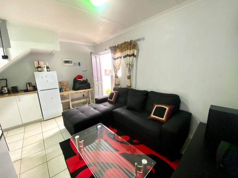 Open-plan living area featuring tiled flooring and a compact kitchen corner with built-in cabinetry, providing a functional layout for apartment living.