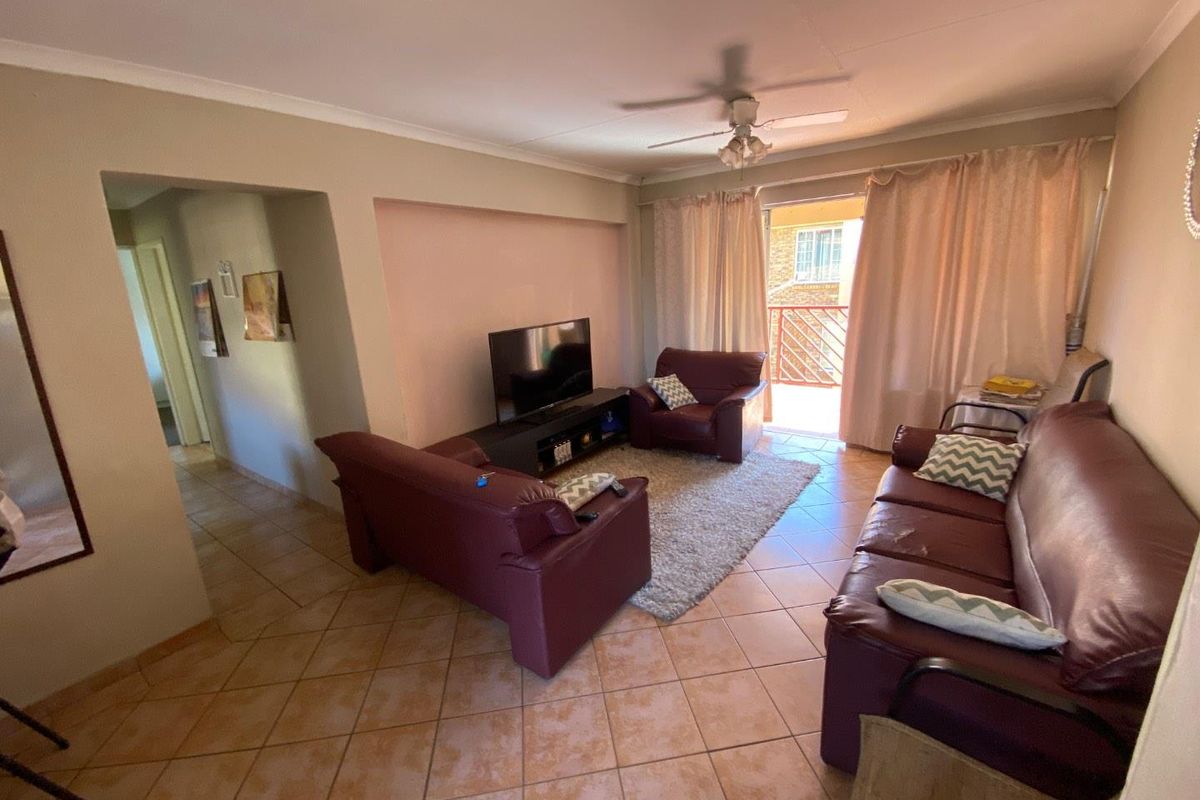 A living room featuring tiled flooring, a ceiling fan, and direct access to a balcony through sliding glass doors.