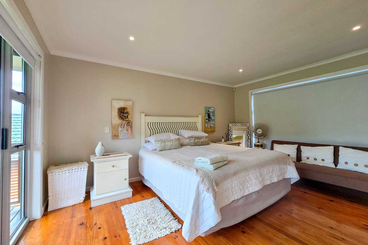 Spacious bedroom featuring polished timber flooring, recessed downlighting, and large glass sliding doors providing access to the exterior.